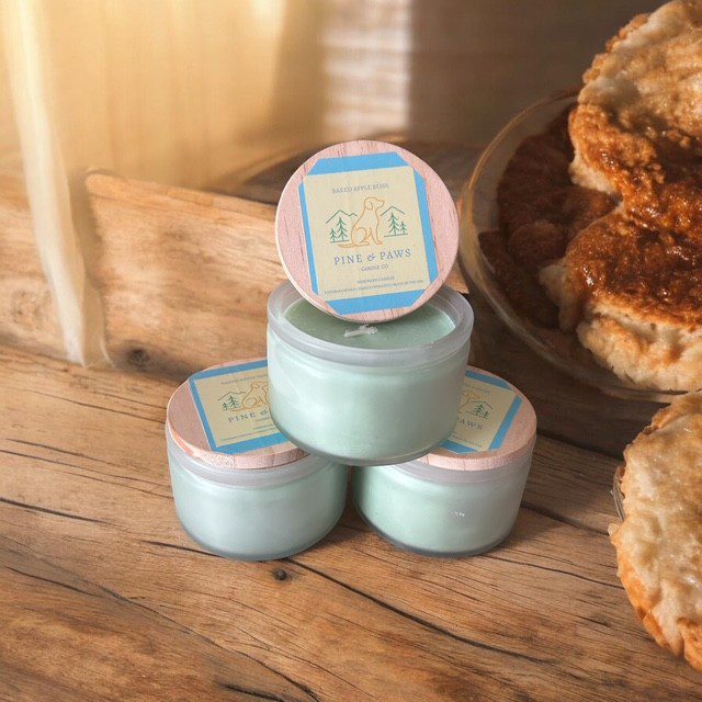 Three mint green cosmetic jars stacked on rustic wooden surface with warm sunlight.