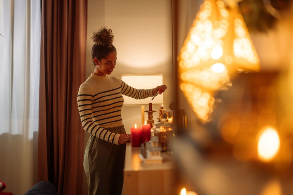 Woman lighting candles in cozy room.