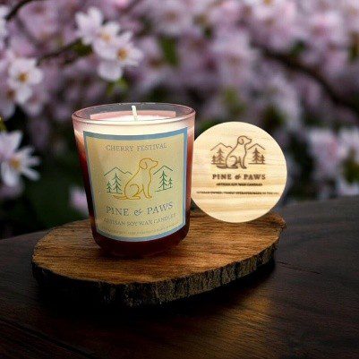 Decorative scented candle with floral backdrop on wooden surface.