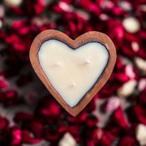 Heart-shaped candle surrounded by rose petals.
