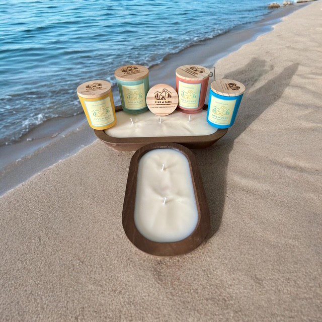 Candles and a soap mold on a sandy beach near the water.