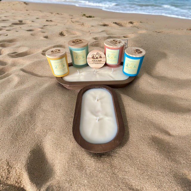 Sunscreen lotions and a foot-shaped sand mold on a sandy beach.