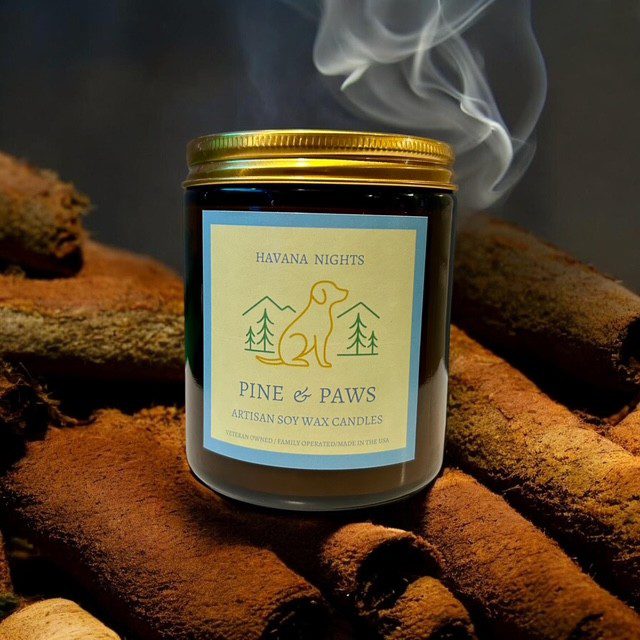 A lit scented candle emitting smoke on a cozy surface.