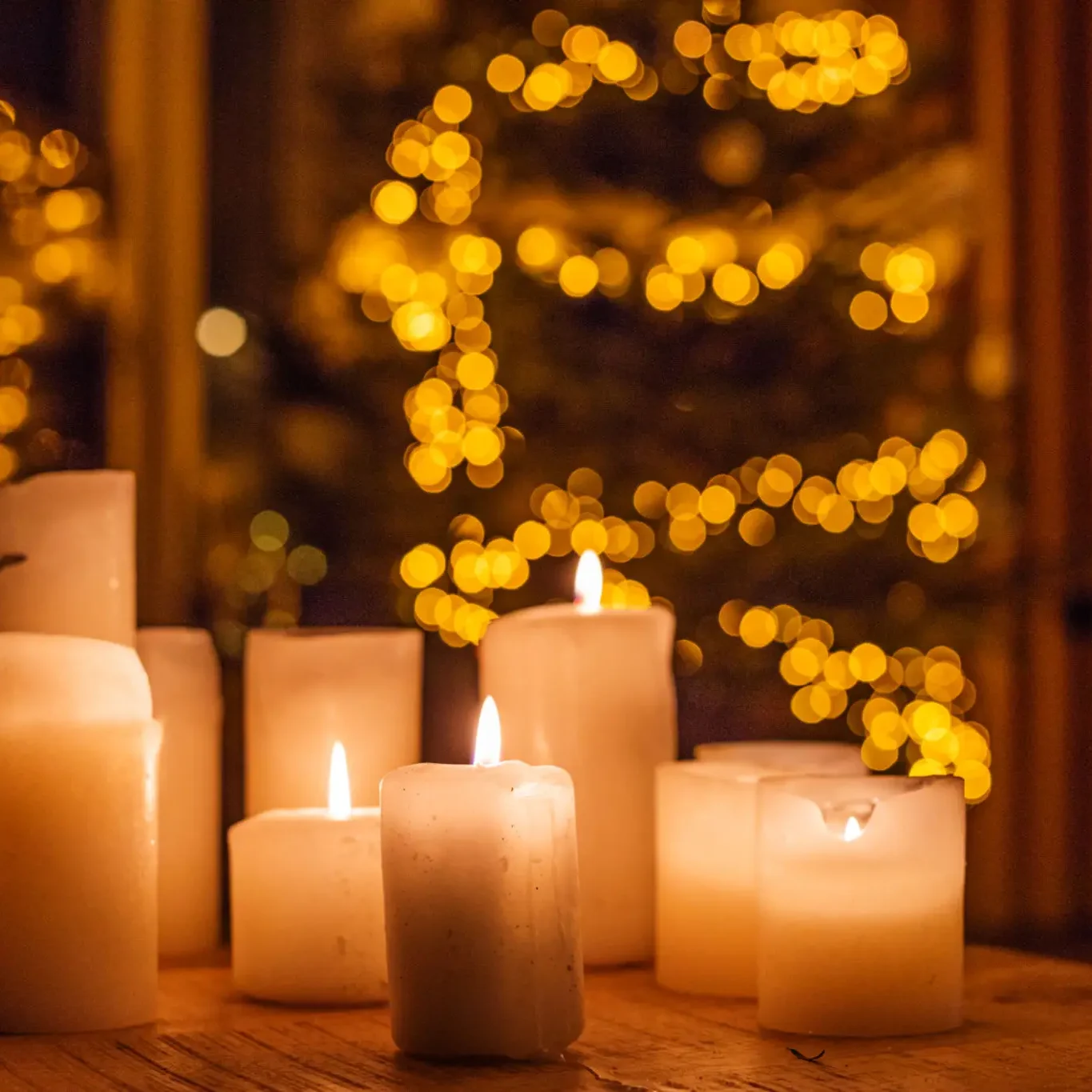 Glowing candles with blurred festive lights in the background.